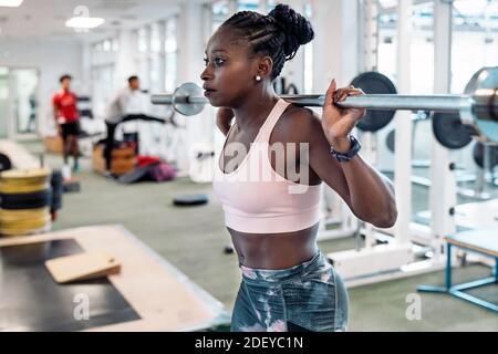 Photo d'un sprinter afro-américain debout devant un poids de levage de miroir dans la salle de sport Banque D'Images