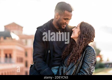 Photo de stock du moment heureux de couple interracial d'amoureux regardant les uns les autres. Ils sont à Madrid Banque D'Images