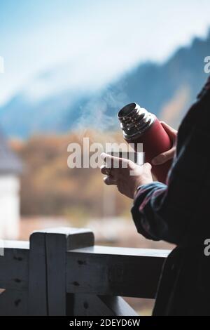 Une fille verse le thé d'un thermos sur un fond de montagnes Banque D'Images