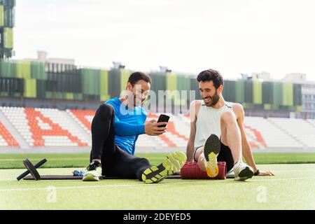 Photo de deux athlètes amis qui prennent une pause en utilisant le téléphone dans la piste sportive. Banque D'Images