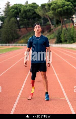 Photo de l'athlète d'homme handicapé debout sur la piste de course et regardant l'appareil photo. Banque D'Images