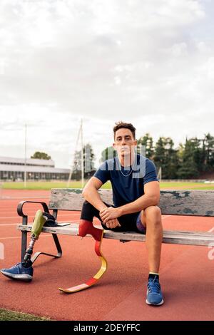 Photo de l'athlète d'homme handicapé assis sur un banc et regardant l'appareil photo. Banque D'Images