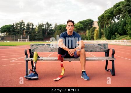 Photo de l'athlète d'homme handicapé assis sur un banc et regardant l'appareil photo. Banque D'Images