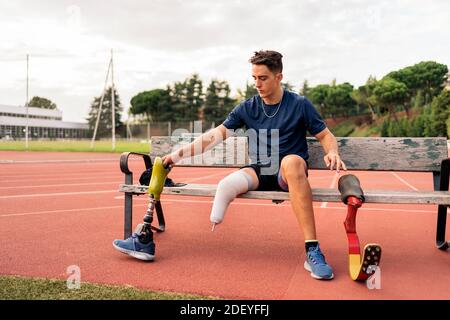 Photo de l'athlète d'homme handicapé assis sur un banc et en mettant sur sa prothèse de jambe. Banque D'Images