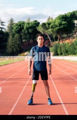 Photo de l'athlète d'homme handicapé debout sur la piste de course et regardant l'appareil photo. Banque D'Images