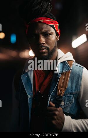 Photo d'un garçon afro-américain sérieux qui regarde l'appareil photo. Il a des dreadlocks et porte un bandana. Banque D'Images