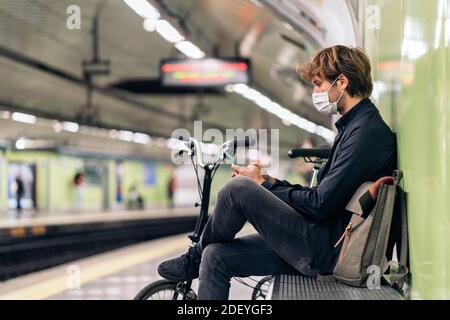 Photo du jeune homme assis dans le métro à côté de son vélo amovible. Banque D'Images