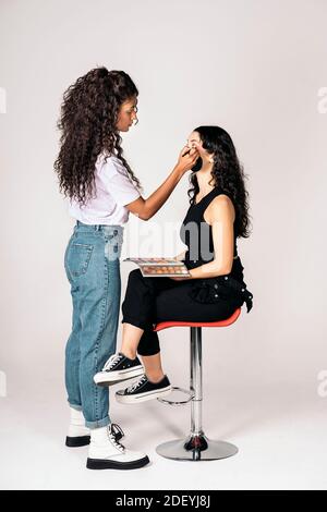 Photo de l'artiste de maquillage heureux utilisant l'ombre pour l'aspect de son client. Banque D'Images