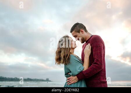 Regard affectueux entre mari et femme au bord de l'océan à coucher de soleil Banque D'Images