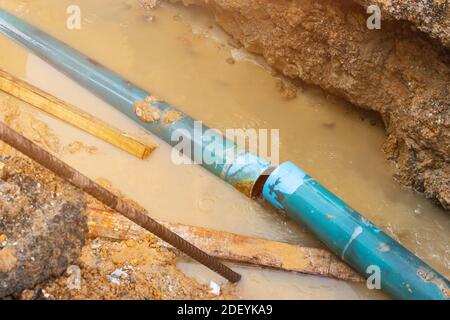réparer le tuyau cassé de la tuyauterie et le débit d'eau dans le trou Banque D'Images