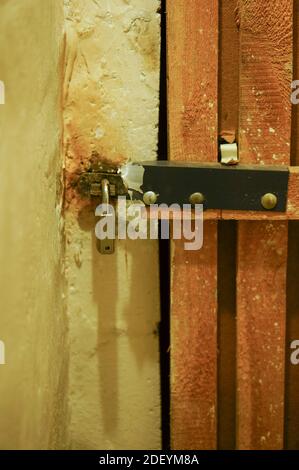 Un cliché vertical d'une porte de sous-sol verrouillée en bois à l'intérieur un couloir sombre Banque D'Images