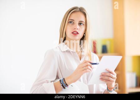 jeune femme avec un crayon et un folio dans un bureau travaillant Banque D'Images