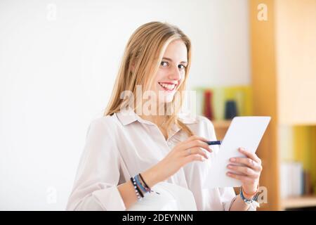 jeune femme avec un crayon et un folio dans un bureau travaillant Banque D'Images