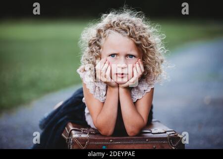 portrait d'une belle fille blonde avec boucles et mains sur son visage Banque D'Images