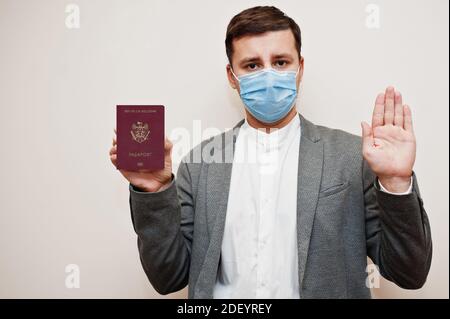 Homme européen en tenue officielle et masque facial, montrer passeport Moldavie avec stop main. Confinement du coronavirus en Europe concept de pays. Banque D'Images