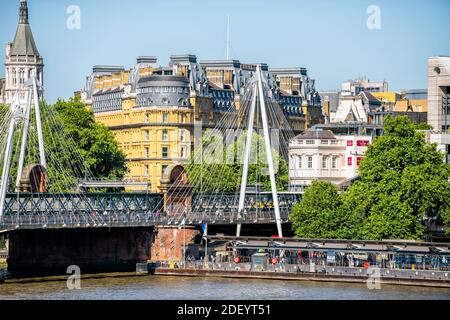 Londres, Royaume-Uni - 22 juin 2018 : pont piétonnier Hungerford en ville avec vue sur les personnes traversant la Tamise le jour d'été ensoleillé et Corinthia Hotel SIG Banque D'Images