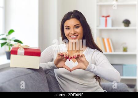 Bonne jeune femme amoureuse de faire un geste en forme de cœur et de dire Merci pour le cadeau de Saint-Valentin Banque D'Images