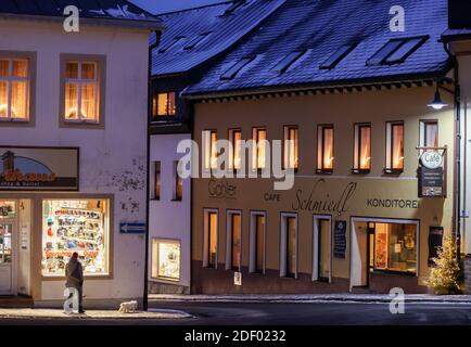 Oberwiesenthal, Allemagne. 02e décembre 2020. Une femme marche avec son chien devant une fenêtre illuminée dans une rue déserte. Dans aucun autre État fédéral, la pandémie de Corona ne se propage actuellement aussi rapidement qu'en Saxe. Par conséquent, des mesures plus strictes sont maintenant en place, y compris des restrictions de sortie. Credit: Jan Woitas/dpa-Zentralbild/dpa/Alay Live News Banque D'Images