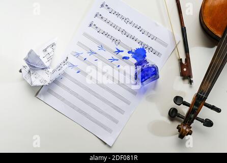 Feuille de musique avec chanson folklorique manuscrite tous les oiseaux sont déjà ici, pot d'encre renversé, empreintes d'oiseaux et une colombe d'origami, violon et arc sur t Banque D'Images