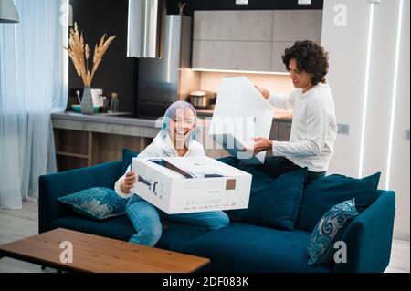 Un jeune couple heureux qui débarque la toute nouvelle console de jeu Sony PlayStation 5 chez lui. Moscou - novembre 28 2020. Banque D'Images