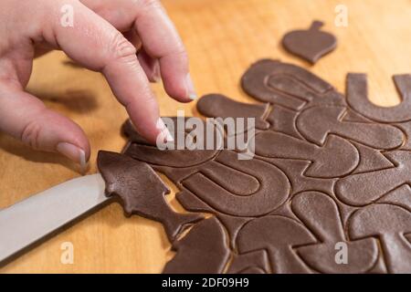 Couper les biscuits de pain d'épice de pâte brute roulée. Pâtisserie traditionnelle douce de Noël ou du nouvel an. La main femelle porte une confestion en forme de poisson. Banque D'Images