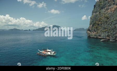 Gros plan en bateau à passagers à la baie océanique avec falaise verte à la vue aérienne. Paysage tropical sur une plage de sable avec des touristes au repos. Gros plan paysage de port à l'île d'El Nido, Philippines, Asie Banque D'Images