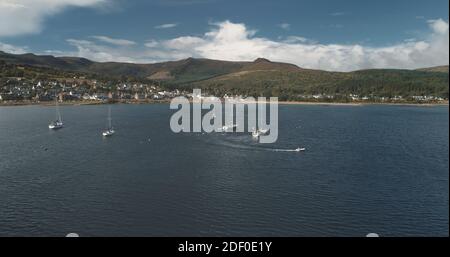 Course de yacht à l'antenne Ocean Bay Coast. Passagers en voilier en pleine mer en été par temps nuageux. Paysage cinématographique d'une croisière de luxe en voilier. Port de Brodick sur l'île de montagne d'Arran, en Écosse Banque D'Images