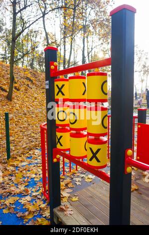 Le plastique coloré TIC TAC TOE XO jeu à la terrain de jeu avec feuilles et arbres en arrière-plan Banque D'Images