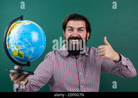 concept de voyage. réussir l'examen. apprendre le sujet. retourner à l'école. bonne journée des enseignants. homme brutal avec barbe, carte du globe géographique. éducation informelle. étudiant assis en classe pendant la leçon. Banque D'Images