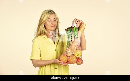 porter un bon achat. un mode de vie sain. prendre soin de votre santé. fitness et manger. nourriture biologique seulement. femme porter une salade d'orange de pomme et du pain dans un sac à cordes. fille aller faire du shopping. Banque D'Images