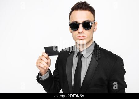 Portrait d'un jeune homme d'affaires heureux, en costume noir, tenant, entre les mains d'une carte de crédit, isolé sur un fond blanc. Vendredi noir, shopping Banque D'Images