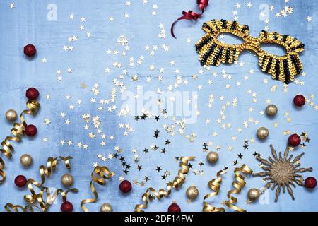 Masque de carnaval doré, étoiles confetti et banderoles de fête sur fond bleu. Plat de Noël, carnaval, concept de fête du nouvel an Banque D'Images