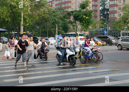 Les gens traversent une rue une fois que les lumières changent de vert après une douche de pluie dans le quartier de Chaoyang, Beijing, Chine Banque D'Images