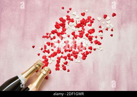 Deux bouteilles de champagne à coeurs rouges et blancs sur fond rose. Espace de copie, vue de dessus. Concept de célébration de la Saint-Valentin Flat Lay Banque D'Images