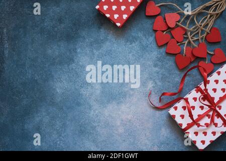 Contexte de la Saint-Valentin. Coeurs rouges et boîtes-cadeaux sur fond bleu. Espace de copie, vue de dessus. Concept de célébration de la Saint-Valentin Flat Lay Banque D'Images