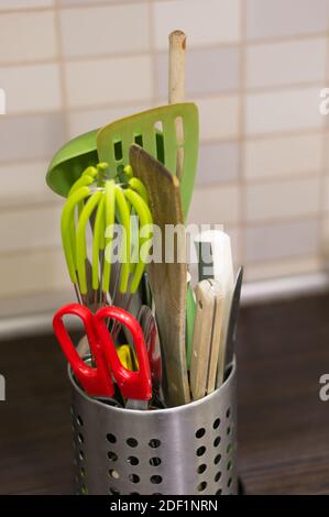 Un cliché vertical de ciseaux, spatules et autres outils de cuisine dans un récipient Banque D'Images