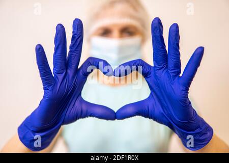 paramédic dans un masque de coronavirus tenant les mains en forme de coeur. de haute qualité Banque D'Images