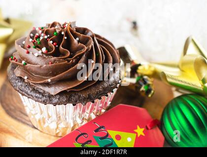 Un gâteau de Noël au chocolat est placé sur une planche entourée d'une étiquette cadeau, d'arcs, d'ornements et d'un père Noël. Banque D'Images