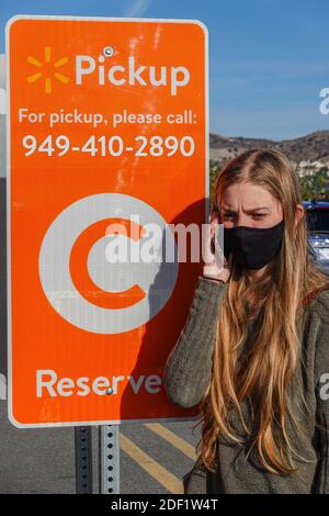 Jeune femme appelant pour un ramassage au bord du trottoir dans un parking Walmart à Foothill Ranch, Californie, États-Unis Banque D'Images