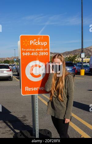 Jeune femme appelant pour un ramassage au bord du trottoir dans un parking Walmart à Foothill Ranch, Californie, États-Unis Banque D'Images