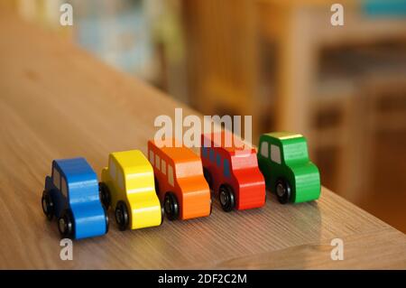 Un gros plan d'une rangée de jouets en bois colorés et bus sur une table en bois Banque D'Images
