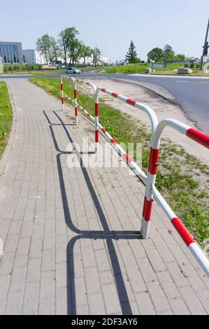 Un cliché vertical de barrières métalliques à côté d'une route et son ombre Banque D'Images