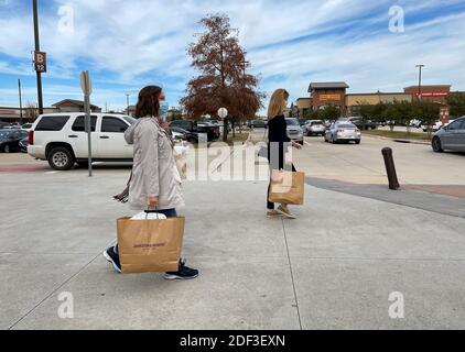 Allen, TX / USA - 27 novembre 2020 : vue rapprochée des personnes portant le masque et portant les sacs de shopping marchant dans les magasins d'usine Allen Premium Outlets sur B Banque D'Images