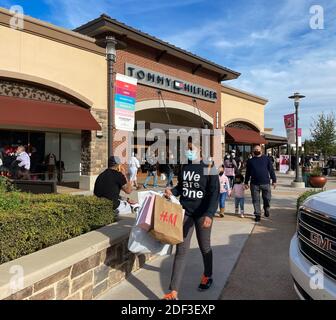 Allen, TX / USA - 27 novembre 2020 : vue rapprochée des personnes portant le masque et portant les sacs de shopping marchant dans les magasins d'usine Allen Premium Outlets sur B Banque D'Images