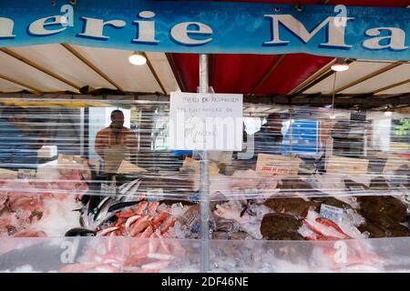 Les gens portant des masques faciaux pour des mesures de protection font leurs courses d'épicerie au marché de la bastille à Paris le 22 mars 2020 avec une protection plastique autour des stands le sixième jour d'un verrouillage strict en France visant à freiner la propagation de COVID-19, le nouveau coronavirus. Un verrouillage strict exigeant que la plupart des Français restent chez eux est entré en vigueur à midi le 17 mars 2020, interdisant toutes les sorties, sauf essentielles, afin de freiner la propagation du coronavirus. Le gouvernement a déclaré que des dizaines de milliers de policiers patrouillaient dans les rues et émettaient des amendes de 135 euros (150 dollars) pour des personnes Banque D'Images