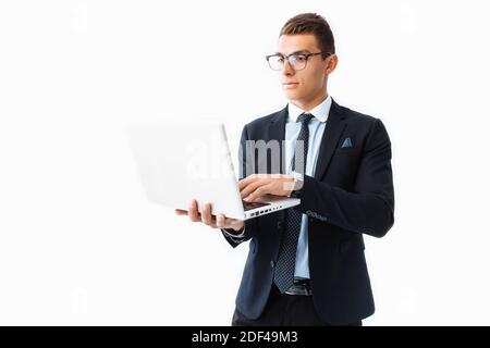 Homme d'affaires confiant avec des lunettes, jeune homme d'affaires beau dans un costume travaillant sur un ordinateur portable, sur un fond blanc Banque D'Images