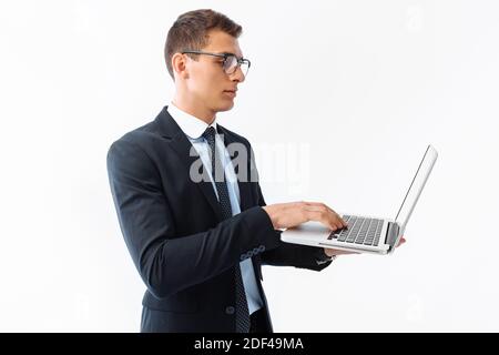 Homme d'affaires confiant avec des lunettes, jeune homme d'affaires beau dans un costume travaillant sur un ordinateur portable, sur un fond blanc Banque D'Images