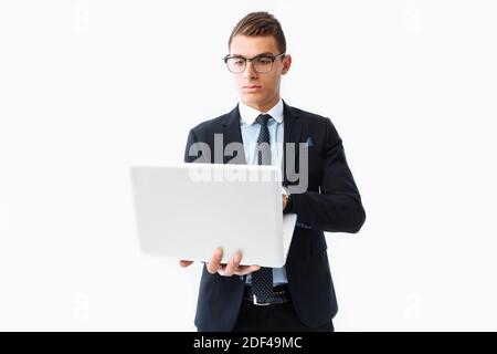 Homme d'affaires confiant avec des lunettes, jeune homme d'affaires beau dans un costume travaillant sur un ordinateur portable, sur un fond blanc Banque D'Images