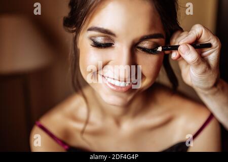 Belle mariée heureuse, artiste de maquillage fait le maquillage de mariage à la fille Banque D'Images