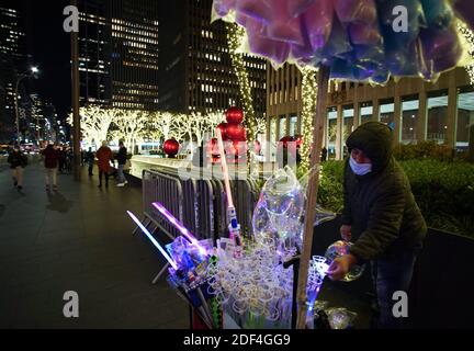 New York, États-Unis. 03ème décembre 2020. Un homme vend des bonbons en coton et des souvenirs de vacances près des décorations de boules de Noël et des décorations de vacances qui sont exposées sur la Sixième Avenue avant la 88e cérémonie annuelle d'éclairage des arbres de Noël du Rockefeller Center au Rockefeller Center à New York le mercredi 2 décembre 2020. Photo de John Angelillo/UPI crédit: UPI/Alay Live News Banque D'Images